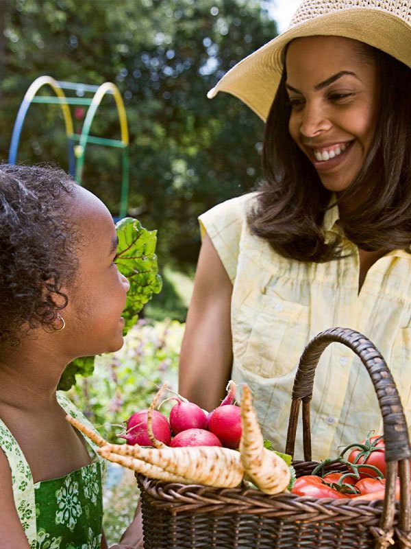 Mother and daughter getting vegetables from garden