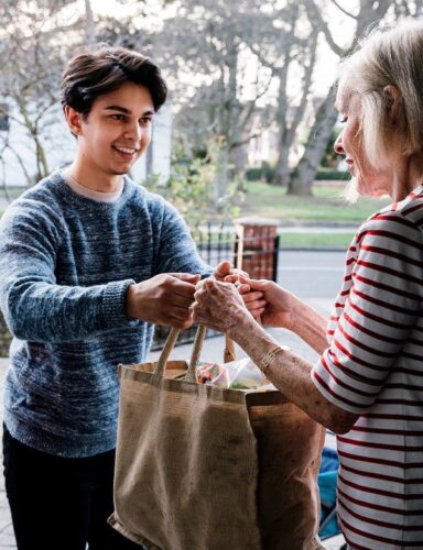 Young Guy Giving Groceries To An Elder Lady