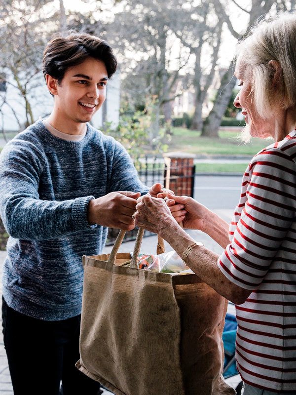 Young guy giving groceries to an elder lady